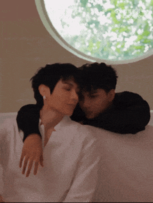 two men are hugging each other in front of a window with a circle in the middle that says ' ao ' on it