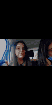a girl with purple hair is sitting in a car and looking at the camera .