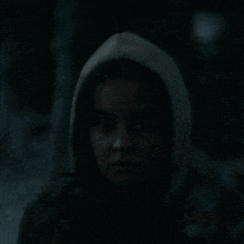 a woman in a hooded jacket is looking at the camera