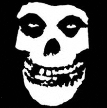 a black and white drawing of a skull with a smile on it on a black background .