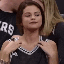 a woman in a basketball jersey is sitting in the stands at a game .