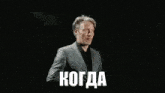 a man in a suit is looking at his watch and the word когда is visible