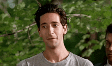 a man in a gray shirt looks at the camera
