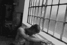 a man without a shirt is leaning against a window