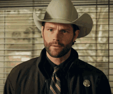 a man wearing a cowboy hat and tie has a badge on his jacket