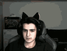 a young man wearing headphones with cat ears on his head is sitting in a chair .