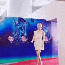 a woman in a white dress walks on a red carpet