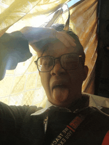 a man wearing glasses is sticking his tongue out and has a shirt that says ' mexico ' on the sleeve