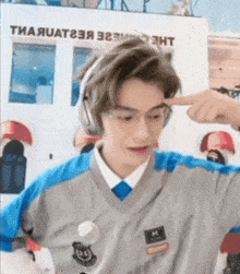 a man wearing headphones is pointing at his head