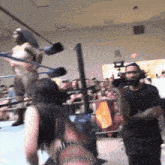 a man in a black shirt is standing in front of a wrestling ring