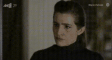 a woman in a black turtleneck sweater is looking at something