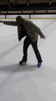 a man in a jacket is ice skating on a rink with his arms outstretched