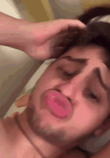 a man with a pacifier in his mouth is making a funny face while laying on a bed .