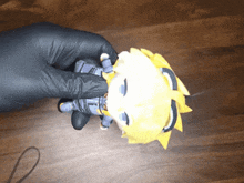 a person wearing black gloves is holding a stuffed animal