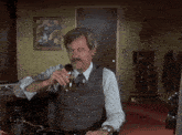 a man in a vest and tie is drinking a glass of whiskey