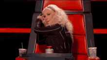 a woman is sitting in a red chair with a starbucks cup on her lap