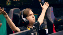 a man wearing headphones is sitting in a chair with his hands in the air