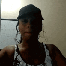 a woman wearing a hat and hoop earrings stands in front of a white board that says " fame "