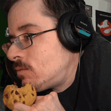 a man wearing a pair of sony headphones eats a cookie
