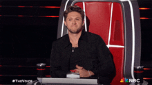 a man sitting in a chair with a nbc logo on the bottom right
