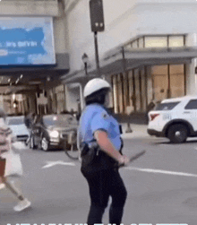 a police officer in a blue uniform is holding a stick in the street
