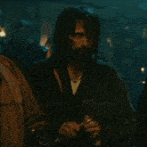 a man with long hair and a beard is holding a bottle in his hand