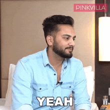 a man in a blue shirt says yeah in front of a pink villa logo