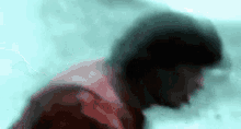 a blurry picture of a man 's face with a red shirt on