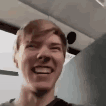 a young man is smiling and making a funny face while sitting on a bus .