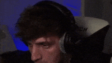 a man is wearing headphones and sitting in a clutch chair .