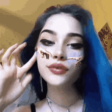 a woman with blue hair has a painting on her face