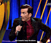 a man in a suit is holding a microphone and says oh i need a wee lie down