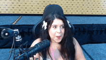 a woman sitting in front of a microphone with a flower in her hair that says ' x ' on it