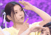 a woman in a yellow shirt is making a gesture with her hand