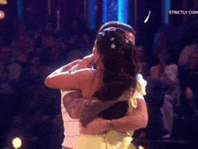 a man and a woman hugging on a stage with strictly.com written on the bottom