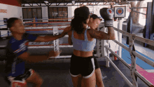 two women are boxing in a ring with a sign that says ' fighting ' on it