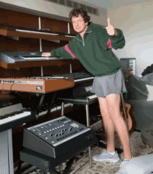 a man giving a thumbs up while standing in front of a keyboard that says yamaha on it
