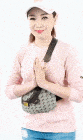 a woman wearing a pink shirt and a white hat is holding a fanny pack and says jiewaty on the bottom