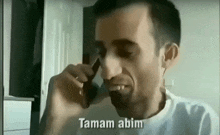 a man is talking on a cell phone and making a face .