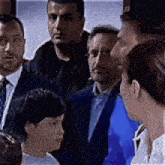 a group of people in suits and ties are standing around a boy in a white shirt .