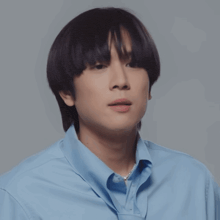 a young man wearing a blue shirt with a pearl necklace