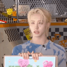 a young man with blonde hair is holding a piece of paper with hearts on it .