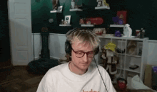 a man wearing headphones and glasses is sitting in a room with a green wall .