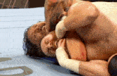 two men are wrestling in a ring and one of them is holding the other 's head