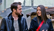 a man and a woman standing next to each other looking at each other