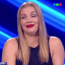 a woman with blonde hair and red lipstick is smiling