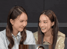 two women looking at each other with one wearing a shirt with the letter p on the front