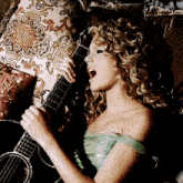 a woman singing into a microphone while holding an acoustic guitar