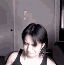 a woman wearing a black tank top and earbuds is making a funny face