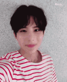 a young man wearing a red and white striped shirt takes a selfie
